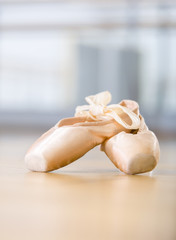 Close-up shot of pointes for ballet lying on the wooden floor