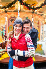 Paar kuscheln auf Weihnachtsmarkt zur Adventszeit