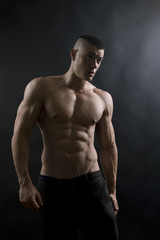 Fototapeta na wymiar Young sexy man with athletic body on black background