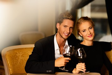 Beautiful young couple with glasses of wine in luxury interior