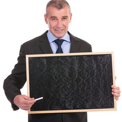 business man holds a small blackboard and points with chalk