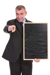 business man with blackboard in hand points at you