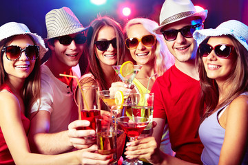 Young friends touching the glasses with each other