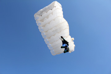 parachutist with white parachute on blue sky