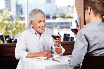 Man and senior drinking wine in restaurant
