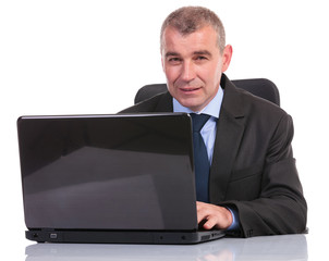 business man works on laptop and looks at you
