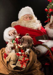 Santa Claus holding envelope and choosing toys from big sack