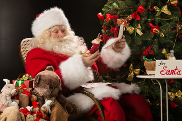 Santa Claus holding envelope and choosing toys from big sack