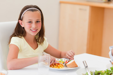Obraz na płótnie Canvas Smiling girl having dinner at dinner table