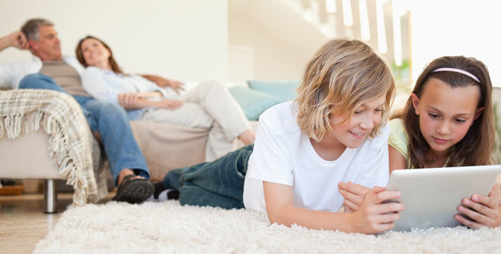Siblings with tablet on the floor