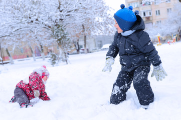 Fototapeta na wymiar Two happy children playing snowball
