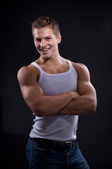 Sexy young man wearing white undershirt and jeans, posing over d