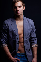 Young sexy macho man with open jacket over dark background