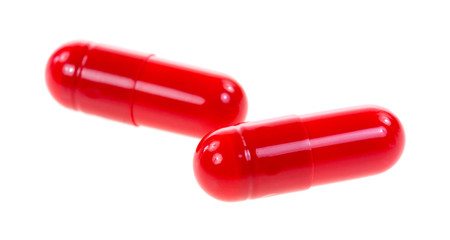 Red antibiotic capsules on a white background