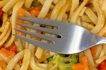 Close view of a fork on cooked noodles