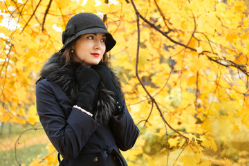 Woman in a black hat on background of autumn tree