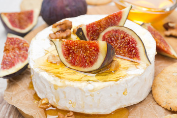 Camembert cheese with honey, figs, walnuts and crackers, closeup