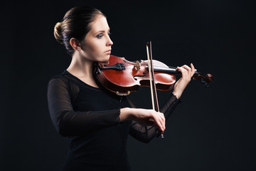 Beautiful young woman playing violin over black