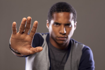 dark-skinned young man showing stop sign with his hand