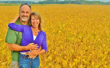 A loving, happy couple standing in a field of yellow flowers.