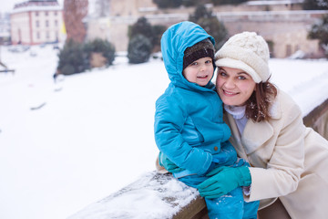 Mother and toddler boy having fun with snow on winter day