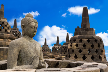 Buddha in Borobudur Temple against blue sky with clouds