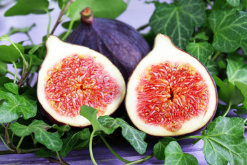 Ripe figs in leaves on wooden table close-up