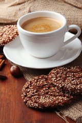 Cup of tasty coffee with tasty cookies, on wooden background