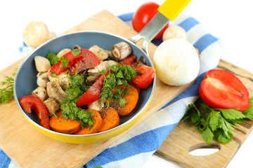Sliced fresh vegetables in pan on wooden board isolated on