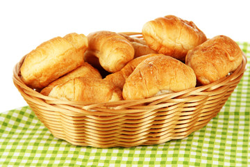 Tasty croissants in wicker basket on table on white background