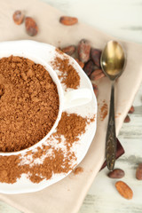 Cocoa powder in cup on napkin on wooden table