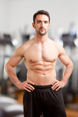 Fit Man Standing With Arms At His Waist in a Gym