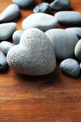Grey stone in shape of heart, on wooden background