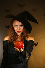 Halloween witch with apple on dark background