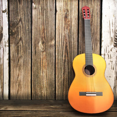 Obraz premium Acoustic wooden guitar leaning on a wooden fence.