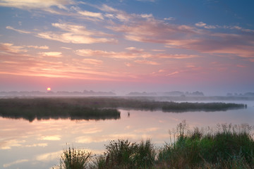 Fototapeta na wymiar dramatic misty sunrise over river
