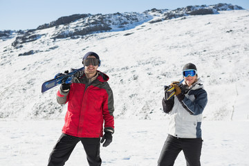 Fototapeta na wymiar Smiling couple carrying ski boards on shoulders on snow