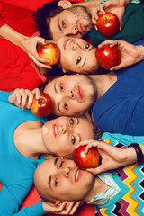 Fototapeta na wymiar Five stylish friends hugging and lying together with apples