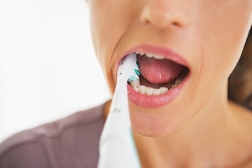 Closeup on young woman brushing teeth