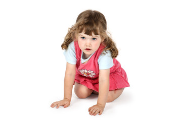 Little surprised girl sits on floor and looks away isolated on w