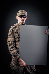 Modern soldier is holding a poster