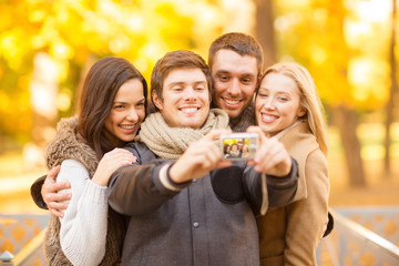 group of friends with photo camera in autumn park