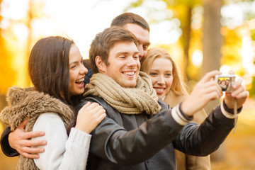 group of friends with photo camera in autumn park