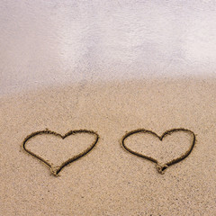 Fototapeta na wymiar Symbole dwóch serc rysowane na piasku, koncepcja miłości