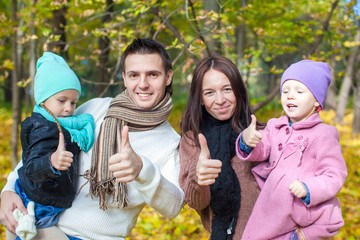 Family of four enjoying autumn vacation and showing a thumbs up