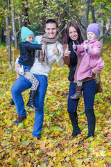 Fototapeta premium Young parents with two little daughters in autumn yellow park