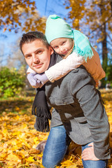 Adorable little girl with happy father having fun in autumn park
