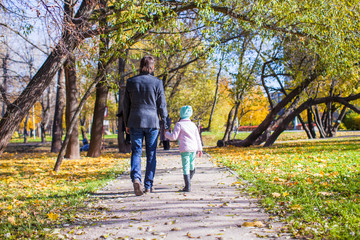Fototapeta premium Rear view of young father and little girl walking in autumn park