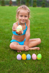 Little adorable girl holding an Easter egg on the grass