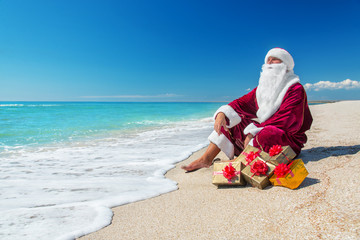Santa Claus with many golden gifts relaxing at beach  - christma